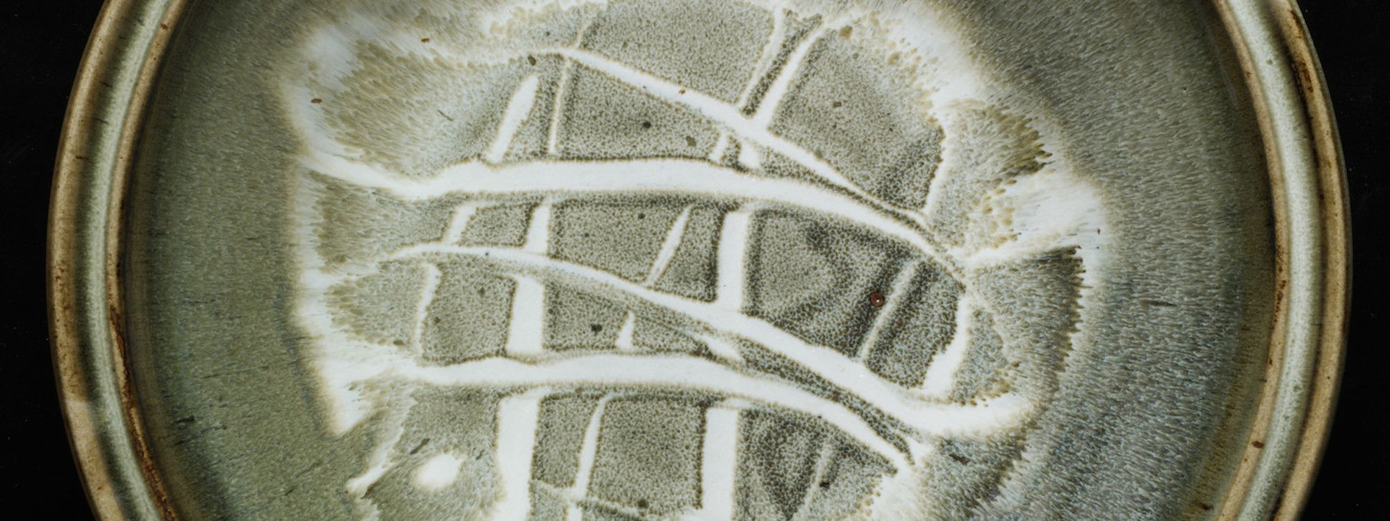 Detail of Edward Hughes, large thrown stoneware dish with slip-trailed decoration and ash glaze with hare’s fur effect. Photo © V&A, London